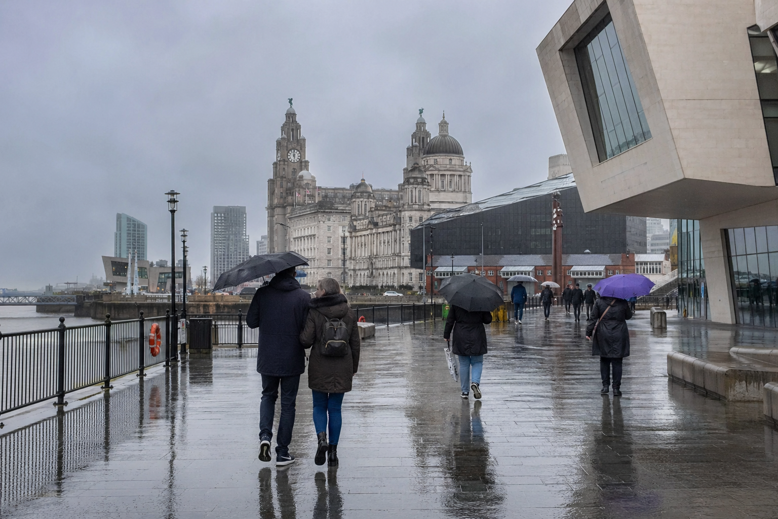 Liverpool waterfront on a rainy afternoon with wet pavements, umbrellas, and the Three Graces in the distance.