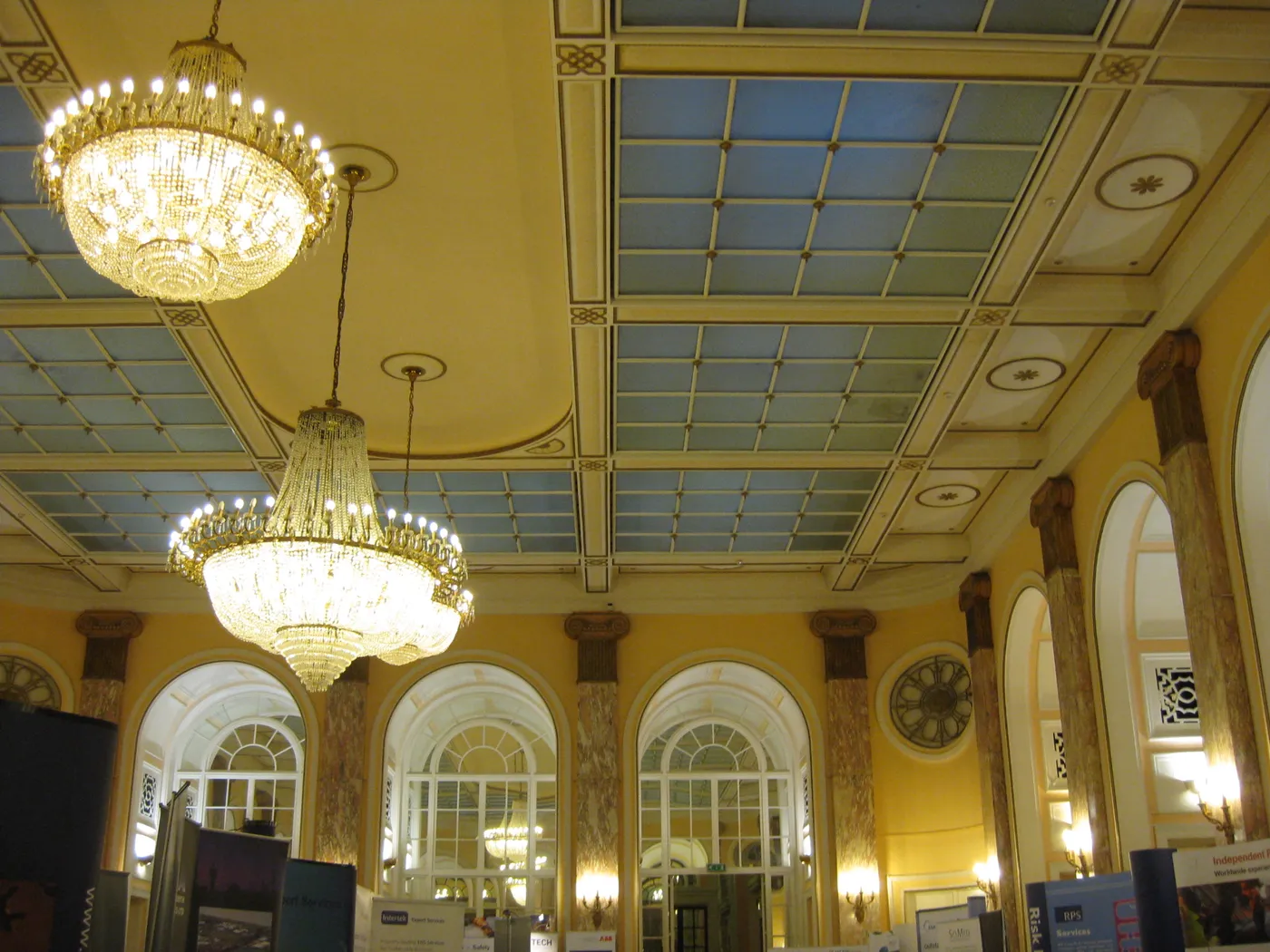 Chandeliers hanging from a coffered ceiling with pale blue panels in a public room at the Adelphi Hotel