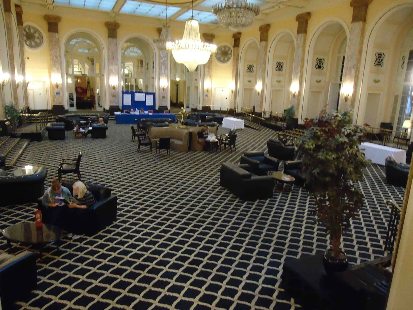 A large public room at the Adelphi Hotel with arched windows, a chandelier and a patterned carpet