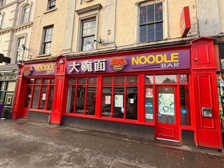Big Bowl Noodle Bar shopfront with a red frontage and purple and yellow sign on Berry Street.