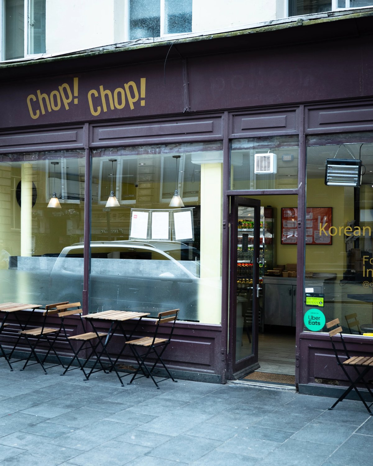 Chop! Chop! shopfront on a city-centre street, with dark red frontage, yellow lettering and outdoor tables.