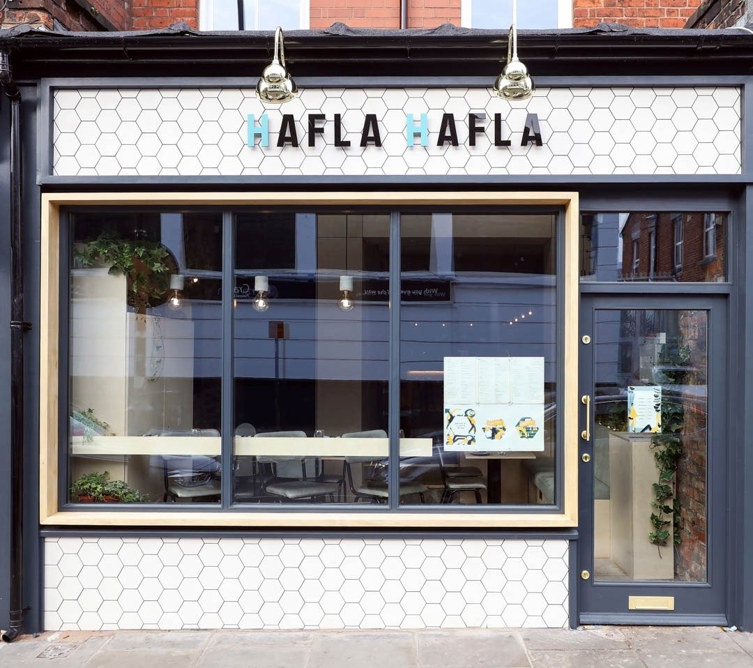 Hafla Hafla shopfront with white hexagon tiles, its name in black and blue lettering and a large front window.