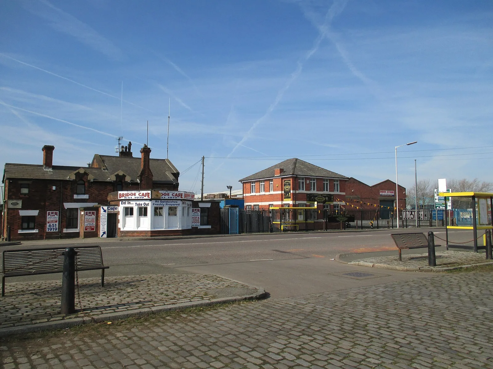 A cobbled area and road junction on Duke Street, Birkenhead, near the docks, with an old brick building and a small bridge control office
