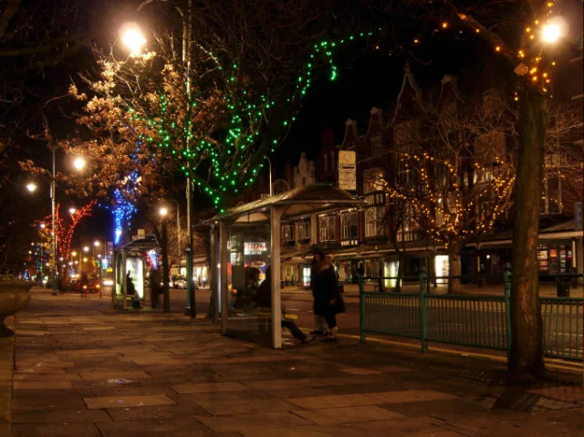 Lord Street in Southport at night, with coloured fairy lights wound through the trees along the boulevard