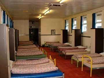A dormitory room at Colomendy with multiple single beds in neat rows, the interior of the buildings that shaped generations of Merseyside school visits.