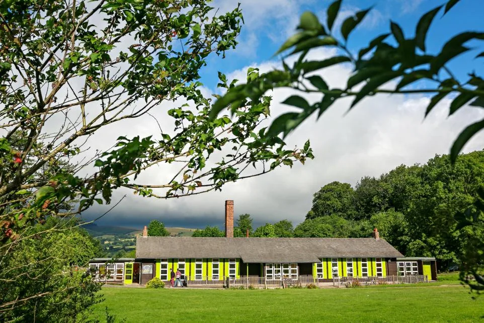 Colomendy estate from above, showing the full 106-acre site with main buildings, accommodation blocks, and surrounding woodland in rural North Wales.