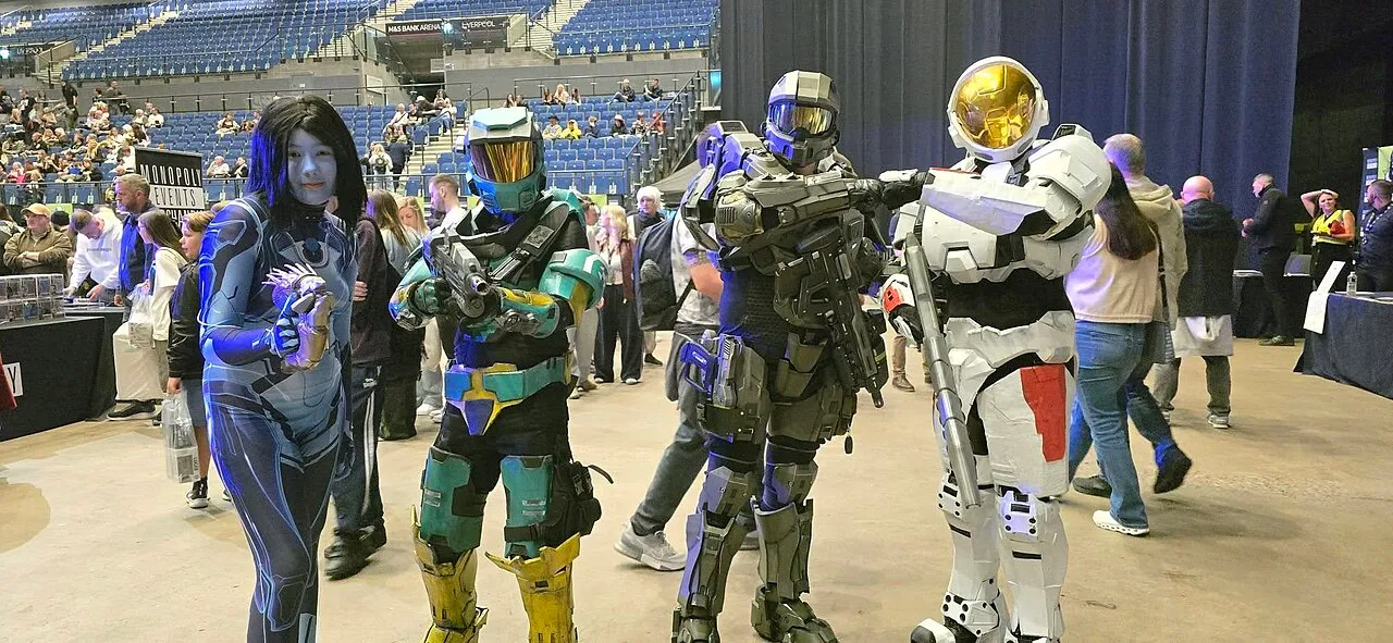 Four cosplayers in Halo-style armour and a blue bodysuit posing on the arena floor at Liverpool Comic Con