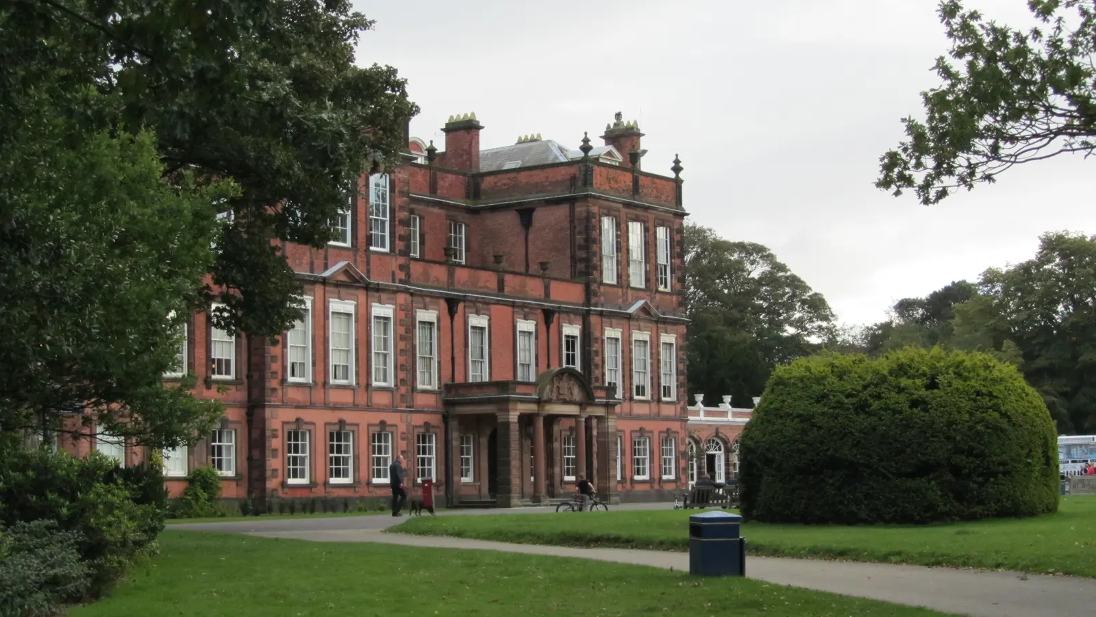 Croxteth Hall seen across open lawn, with its long brick and stone front under a blue sky