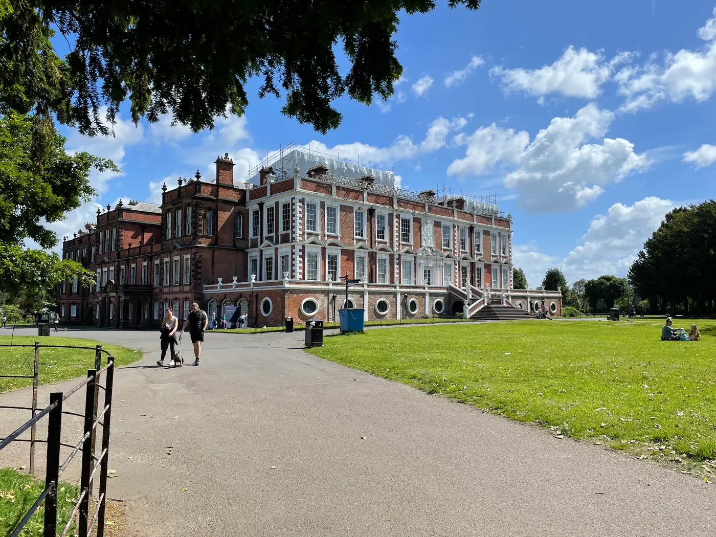 Visitors walking up the main path towards Croxteth Hall on a sunny day, with lawns on either side