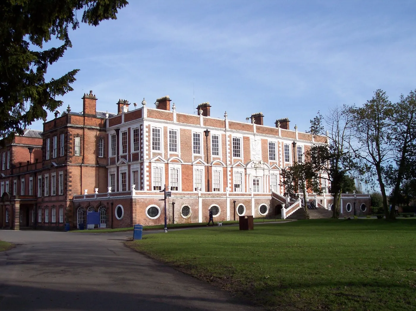 The long red-brick and stone front of Croxteth Hall in sunshine, with a stone staircase up to the main door