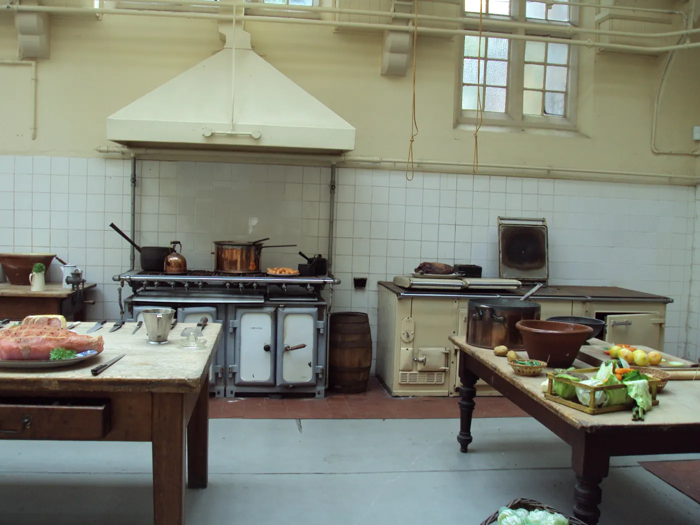 The tiled Victorian kitchen at Croxteth Hall with a range, copper pans and long preparation tables