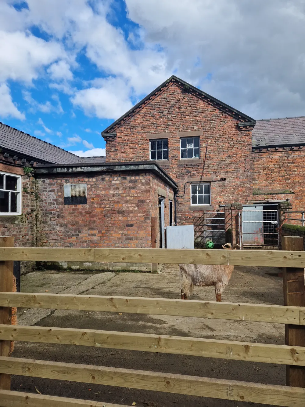 The brick Home Farmhouse at Croxteth Hall with a pig pen and timber fencing in front