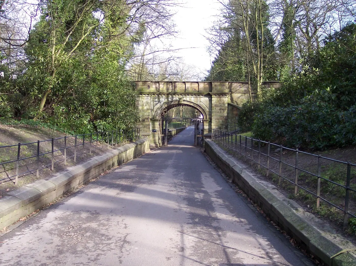 A stone bridge carrying a drive over a sunken path in Croxteth Park, with trees on both sides