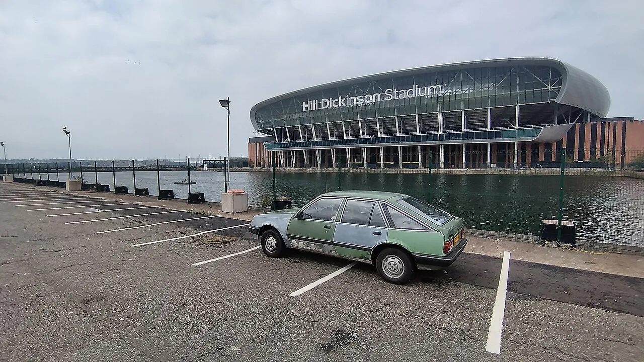 Hill Dickinson Stadium beside Bramley-Moore Dock, with a parked car in the foreground