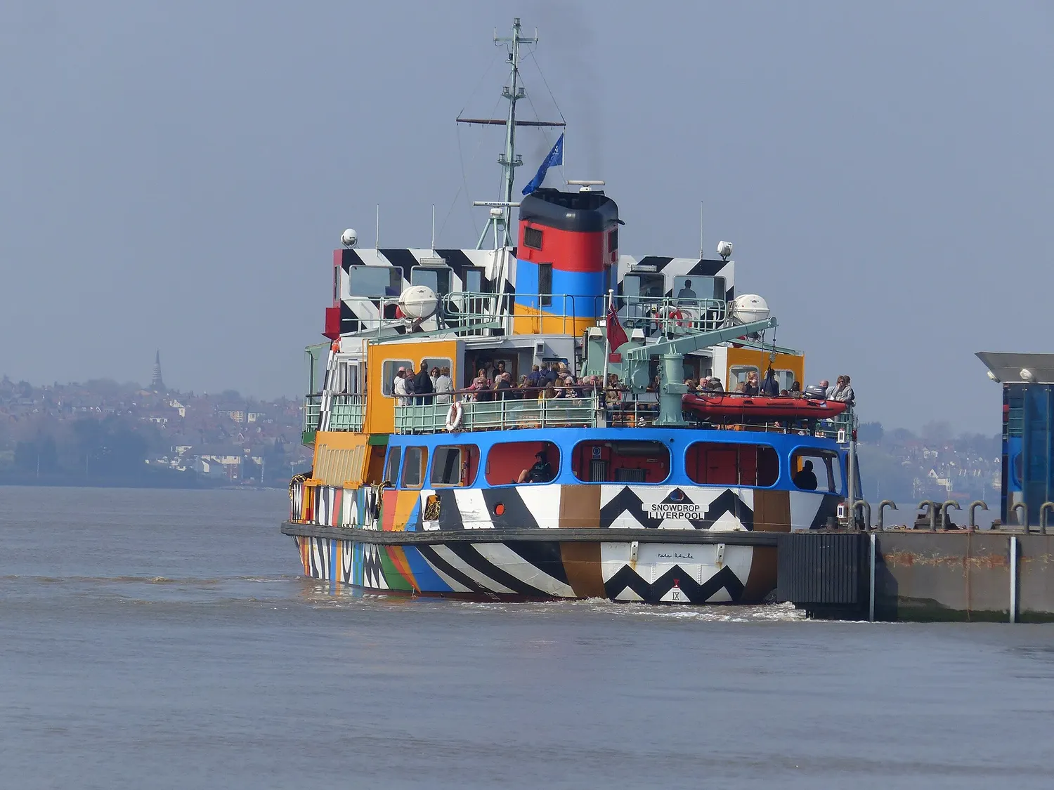 The dazzle-painted Mersey ferry Snowdrop pulling away from the landing stage at Pier Head