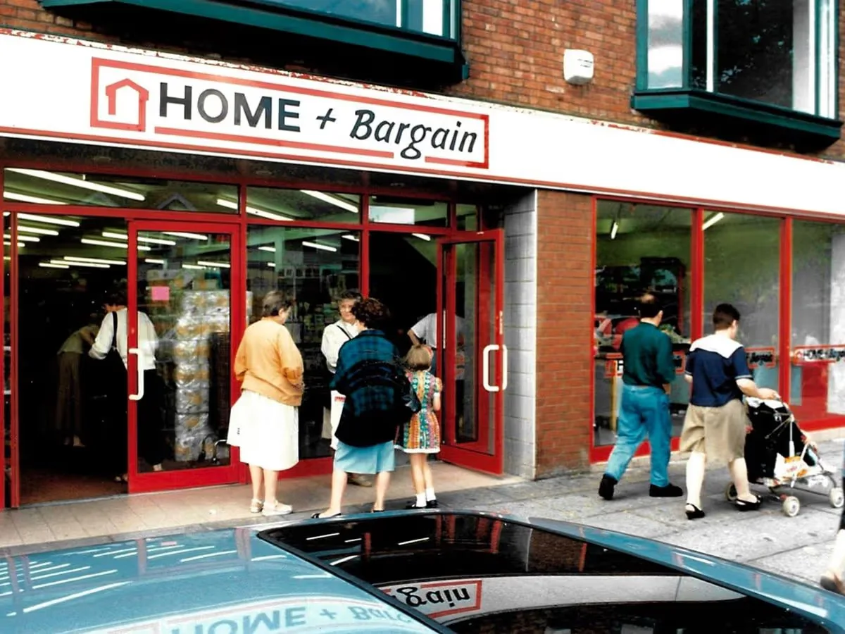 Shoppers going into a Home + Bargain shop front, with the name in black lettering on a white sign with a red outline.