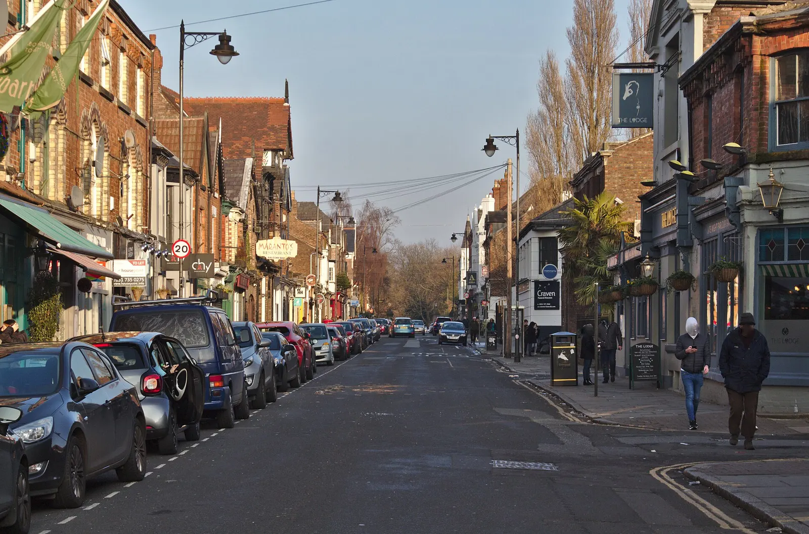 Lark Lane looking towards Aigburth Road with cars parked along both kerbs outside the shops and bars