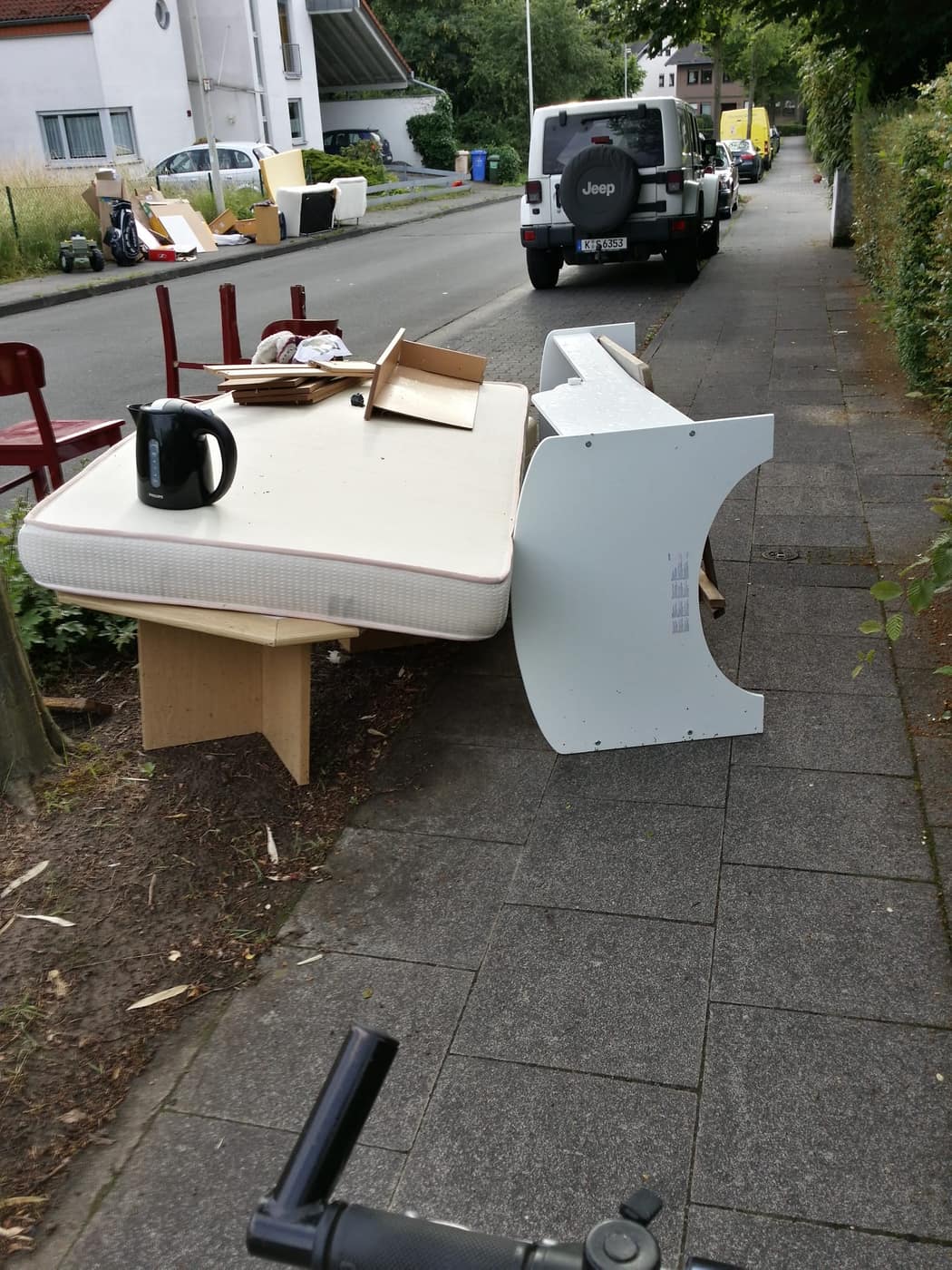 A mattress and wooden chairs placed outside for bulky waste collection