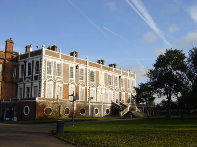 Croxteth Hall, a large red brick country house with tall windows, seen across open lawn