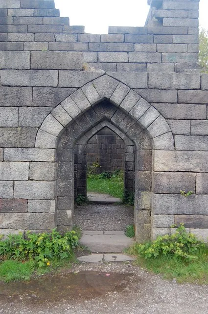 Two triangular headed stone doorways in a thick gritstone wall inside the Rivington castle replica