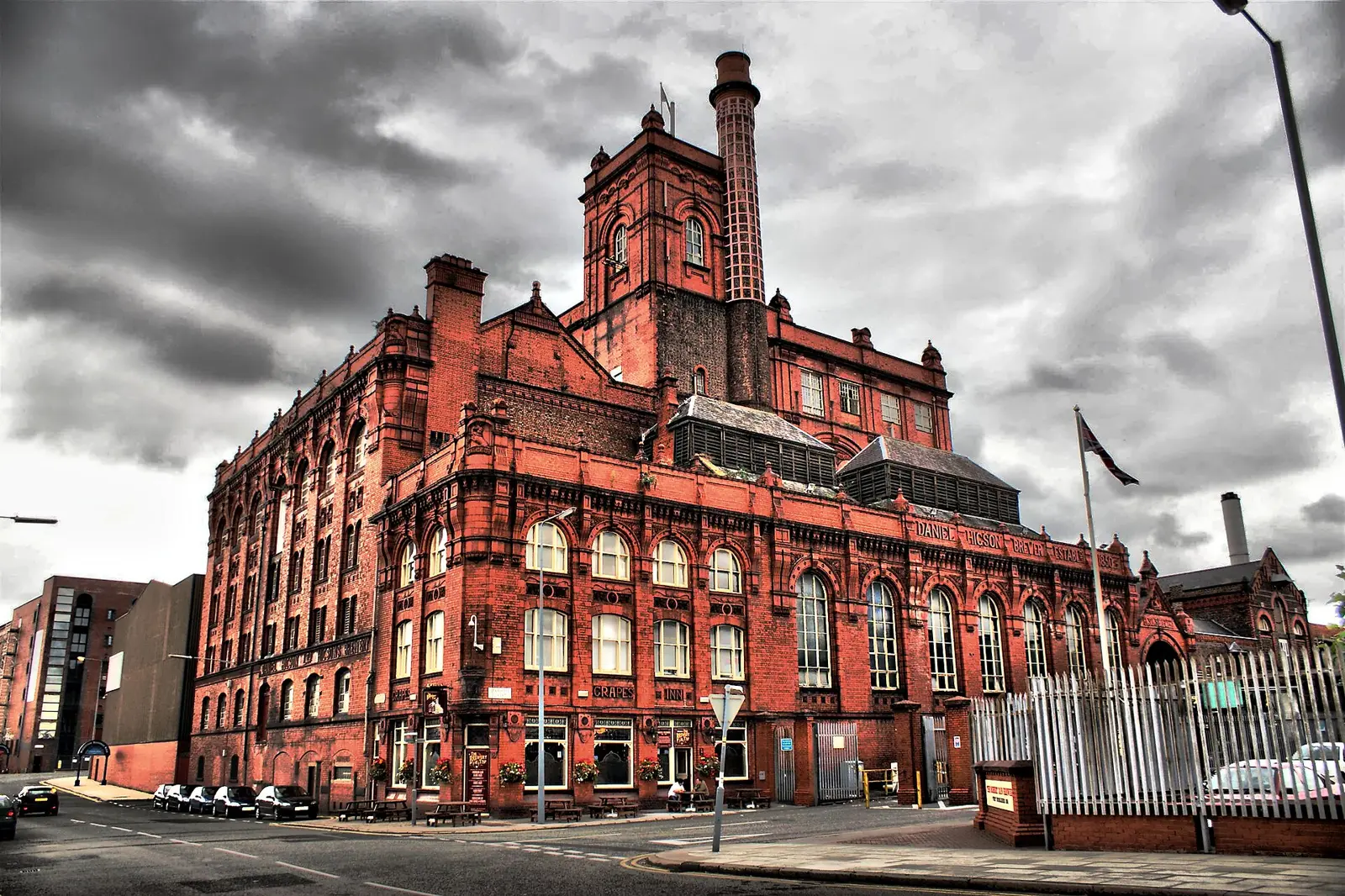 The red-brick Victorian Cains Brewery building with its tall chimney under a grey sky