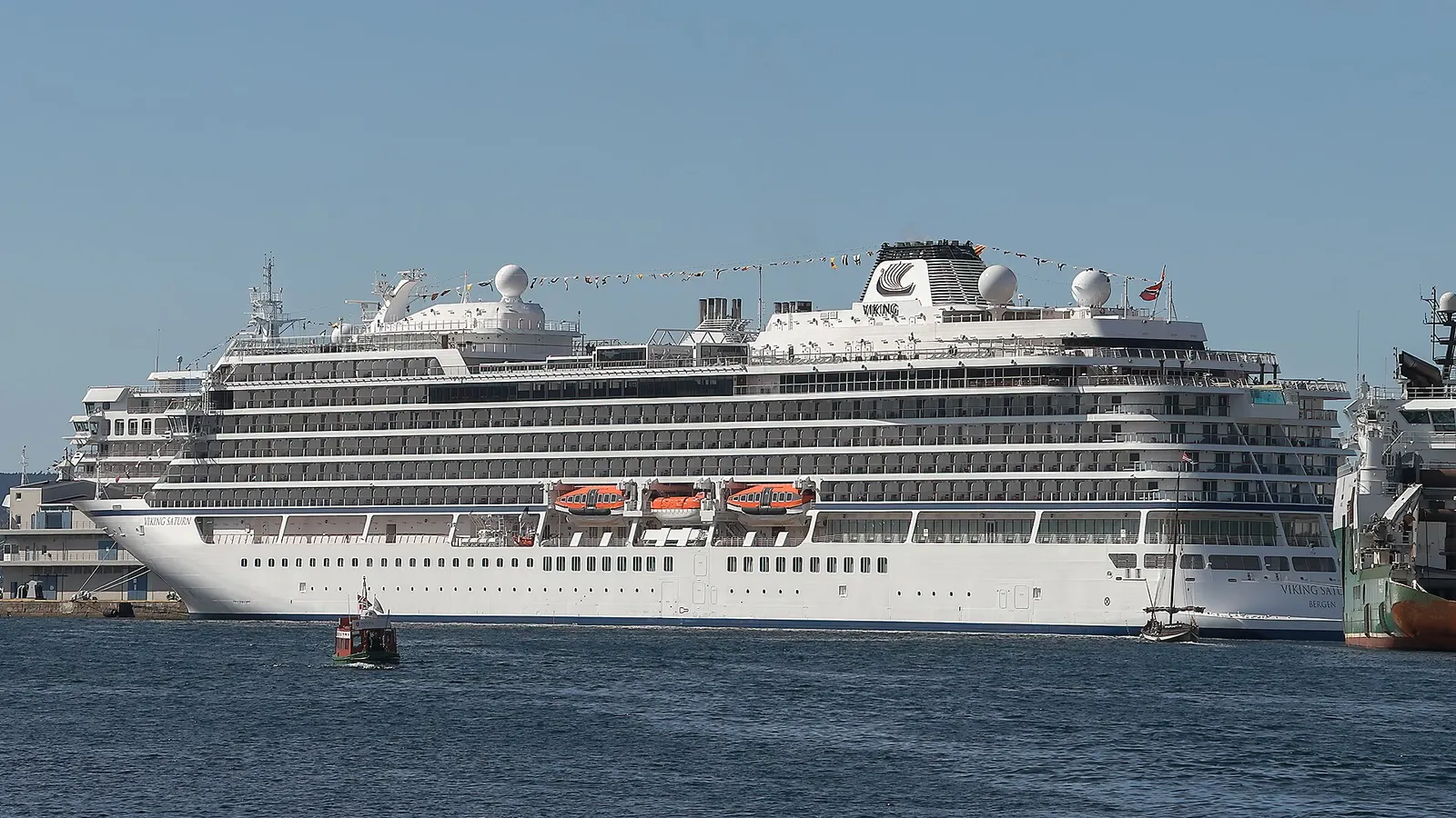 The cruise ship Viking Saturn berthed in Bergen with a small boat passing alongside