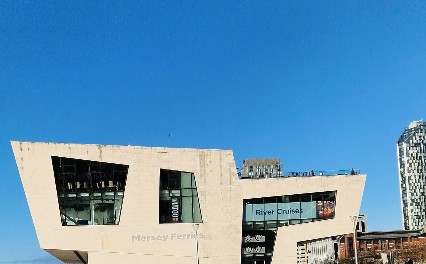 The angular white Mersey Ferries terminal building at Pier Head against a clear blue sky, with River Cruises signage on the side