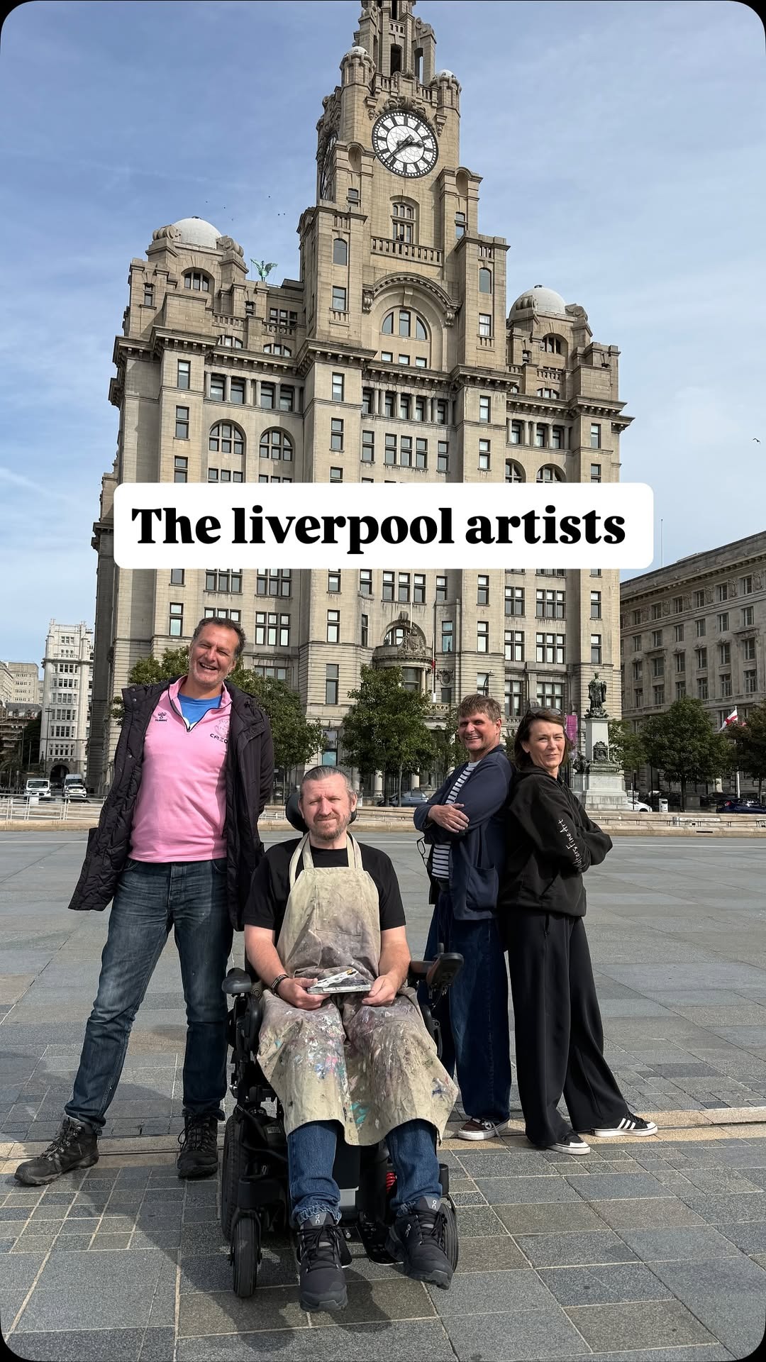 Members of The Liverpool Artists collective standing in front of the Royal Liver Building with painting materials