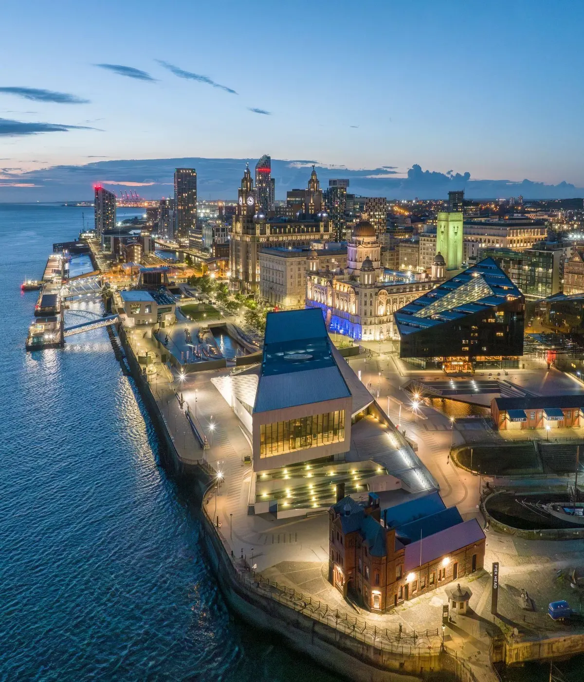 Aerial view at dusk of the Pier Head and Liverpool waterfront, with the Museum of Liverpool, the Three Graces and the landing stages on the Mersey
