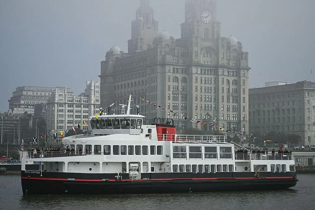 The new Mersey ferry Royal Daffodil, white with a red funnel and black hull, crossing the river in mist with the Royal Liver Building behind