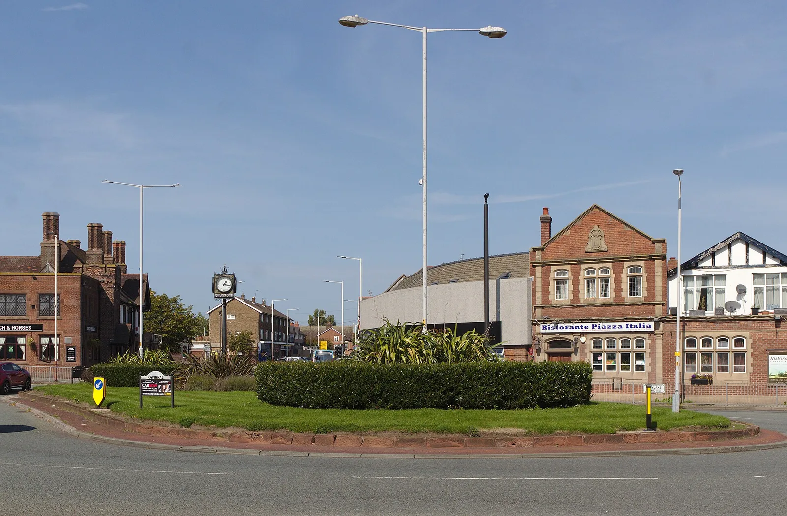 Shops and traffic at Moreton Cross crossroads in Wirral, seen from the central refuge on Upton Road