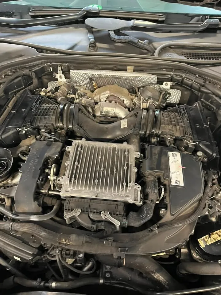 Close-up of a car engine bay with the engine cover removed, showing the turbocharger and the engine control unit